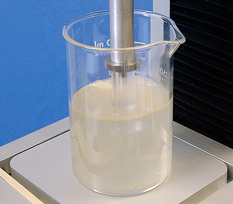 A jug containing mixed carrageenan hydrocolloid with a Perspex compression probe depressing the surface to measure textural firmness